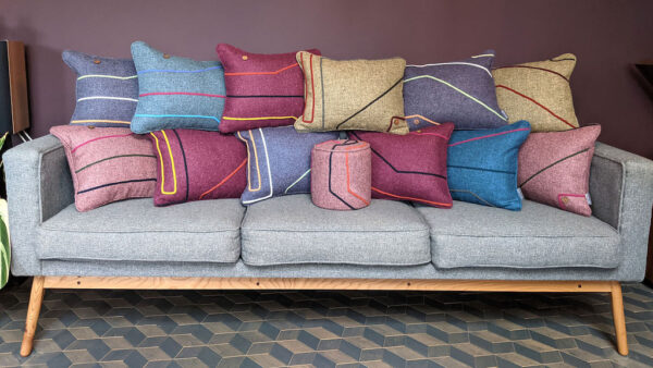 Many multicoloured scatter cushions placed on a grey sofa