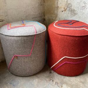 2 footstools in the corner of a faded empty room, one is grey, one is orange